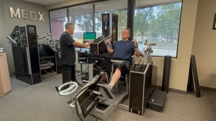 Patient completing supervised, stabilized MedX spinal testing while Armando monitors the equipment at The Center for Total Back Care.